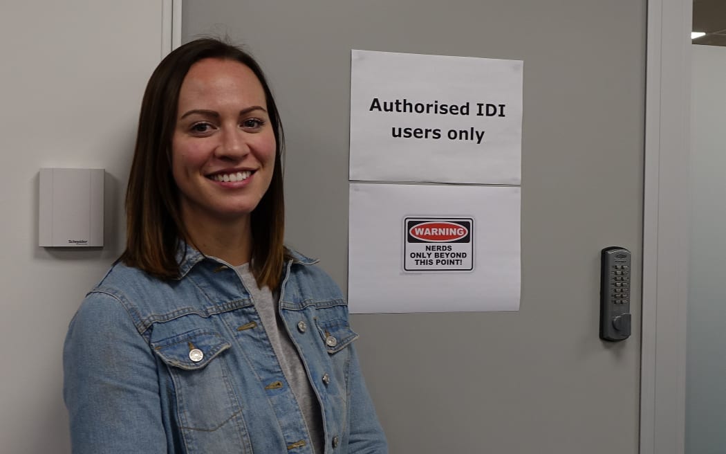 Young women stands outside door with sign saying