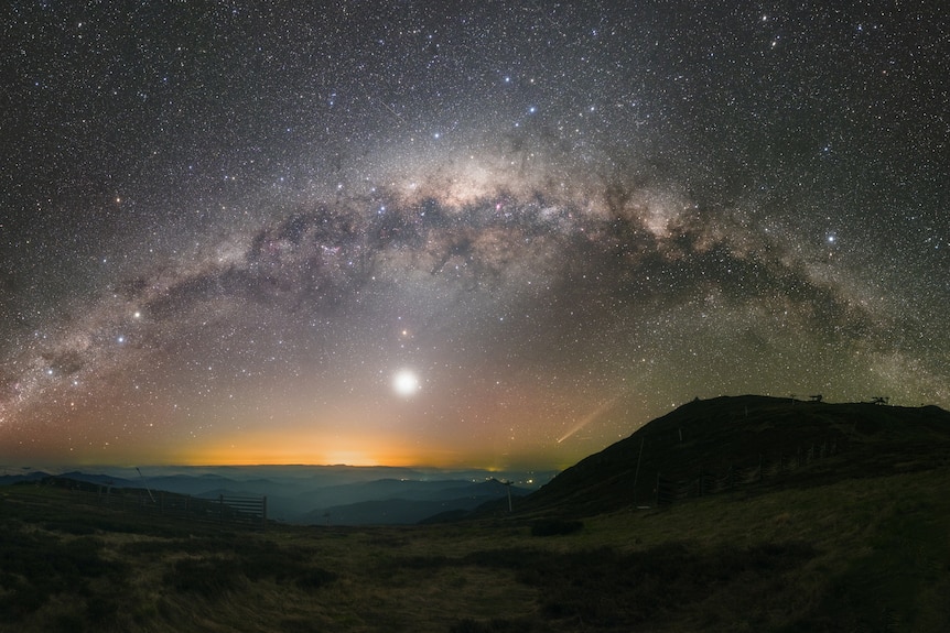 A wide shot of the Milky Way against a coastal landscape.