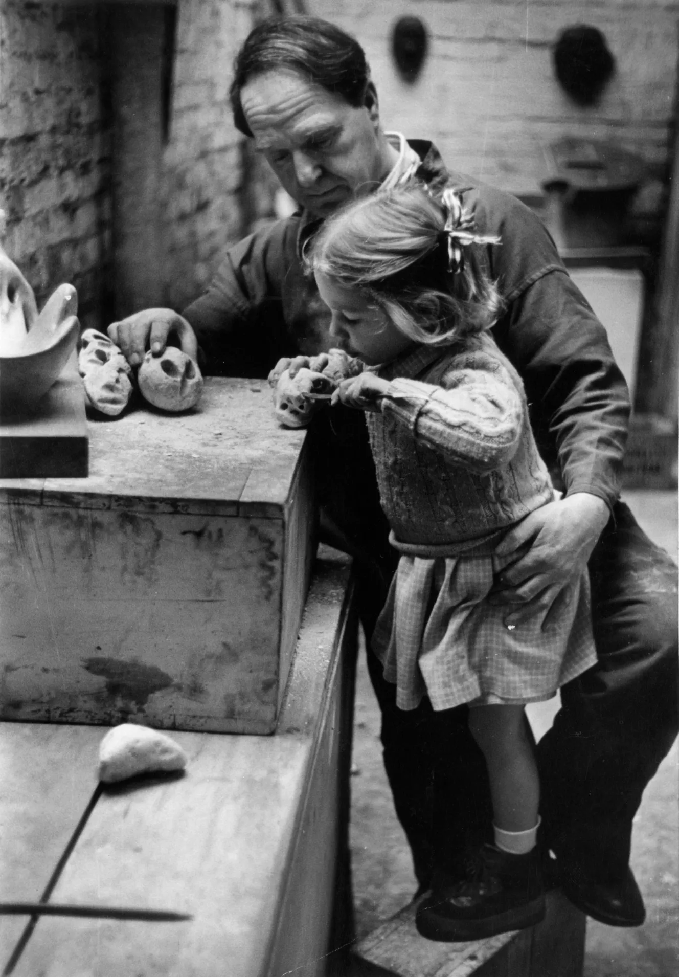 Mary Moore (5 years old) carving a small sculpture, held by her father, Henry Moore.