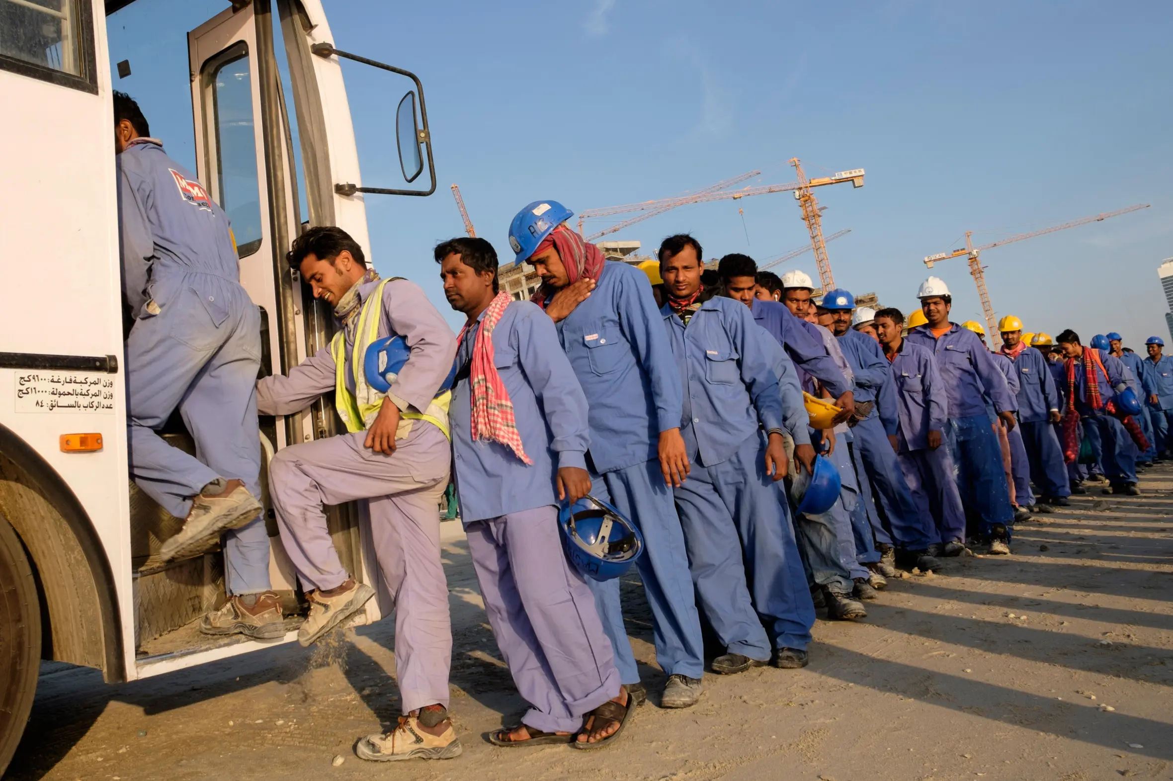 Construction workers in Dubai queuing to board a bus to their living quarters.
