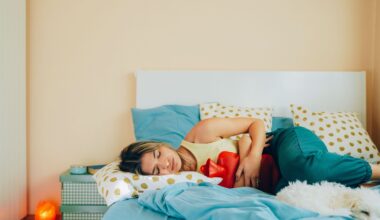 woman laying on her bed holding a hot water bottle to her stomach