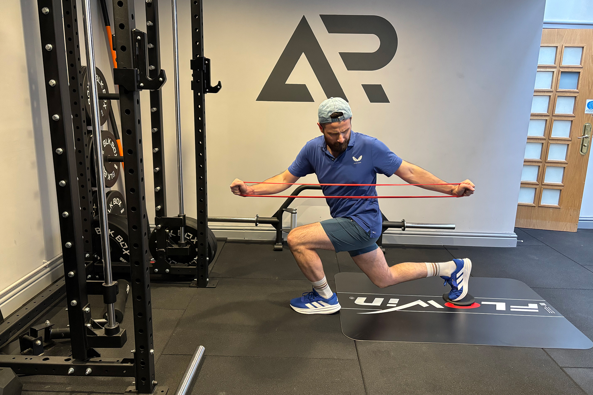 Baz Plummer demonstrating a reverse lunge with band to develop lower body strength