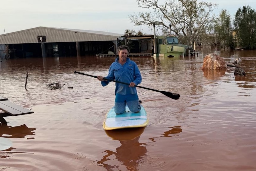 A man paddleboards through a rural property