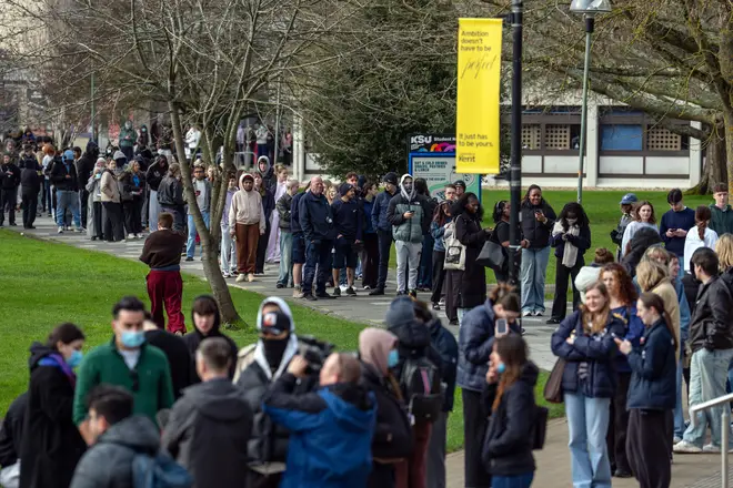 Hundreds of staff and students, some wearing face masks, queue to receive antibiotics at the University of Kent in Canterbury