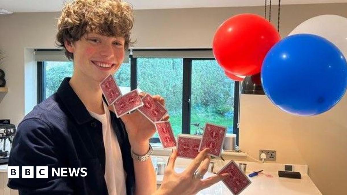 Rafferty in his kitchen smiling and holding playing cards between his fingers