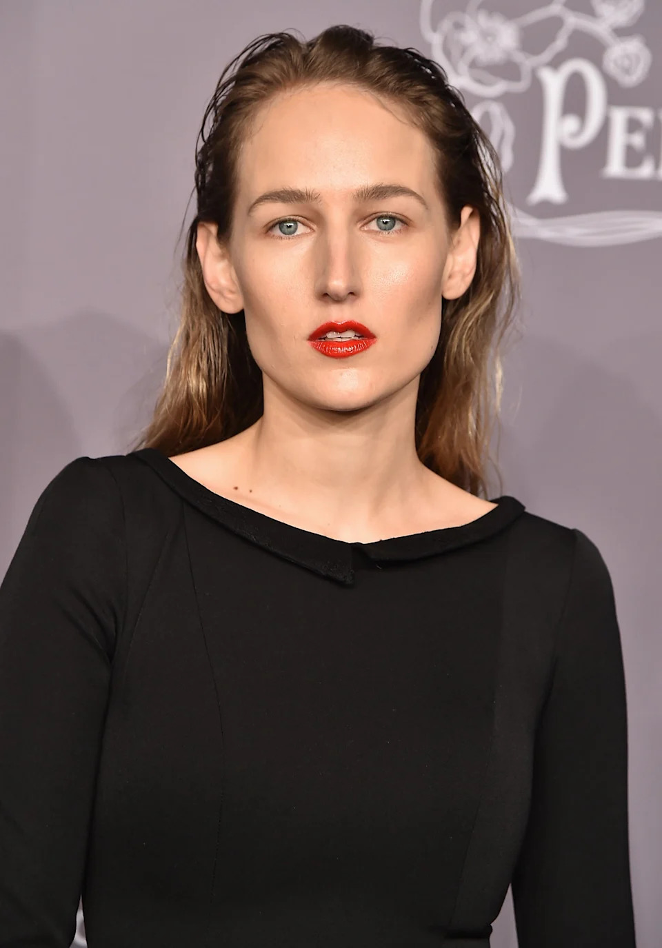 Leelee Sobieski in sleek black dress on the red carpet, with wet hair look and striking red lipstick, posing for the camera