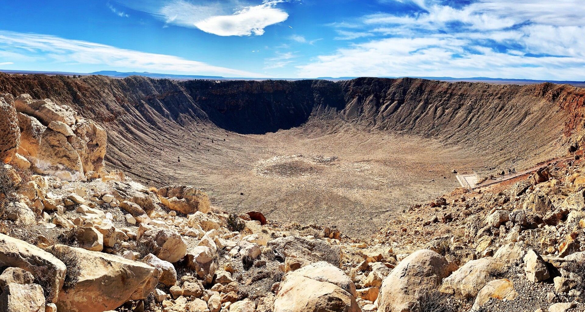 a deep circular crater in a rocky desert landscape