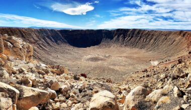a deep circular crater in a rocky desert landscape
