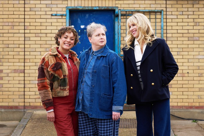 Amandaland Rochenda Sandall as Fi and Siobhan McSweeney as Della, stansing next to Amanda, who's looking at them with a possessed grin on her face