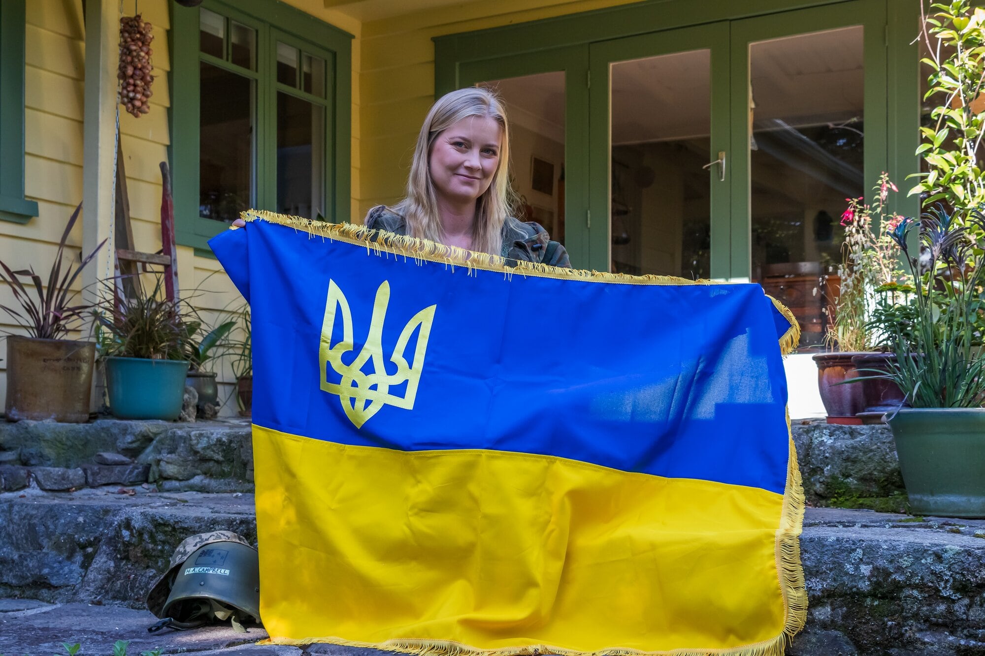  Harriet Campbell, known as ‘Amy in Ukraine’ at home in Tauranga, with a Ukraine flag and her helmet. Photo / Kelly O’Hara