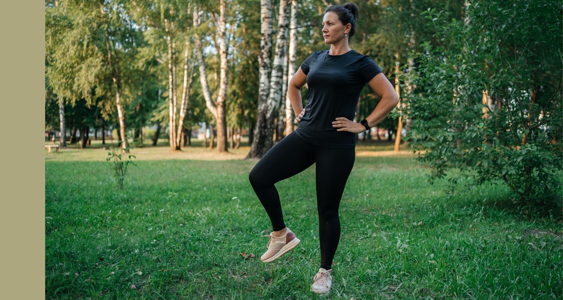 Woman doing hip airplane exercise in activewear standing in green park in the sunshine