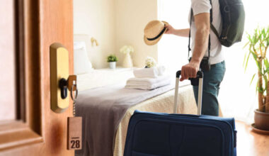 A person placing a sun hat on the hotel bed.