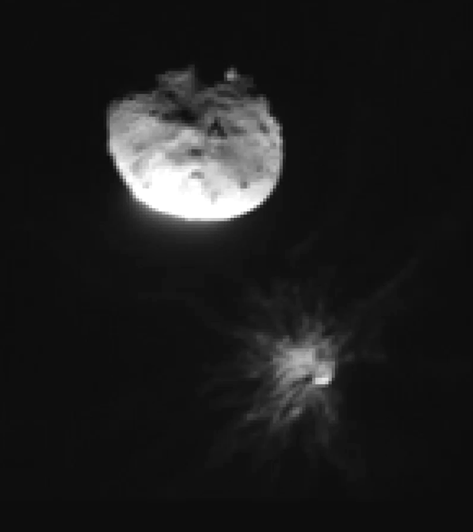 A blurry space rock toward the top left with a bunch of streak-like matter toward the bottom right. The image is black and white.