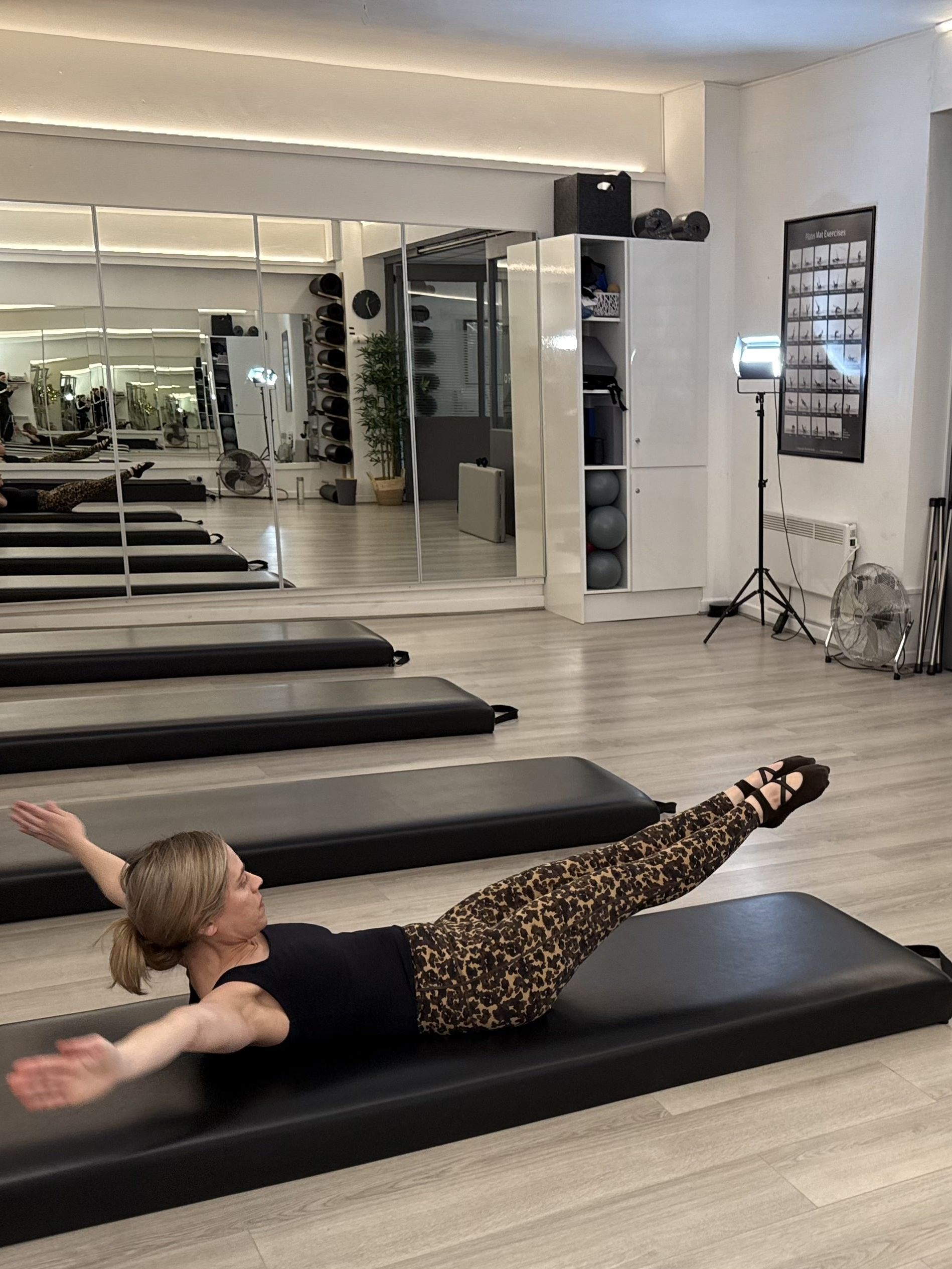 Woman demonstrating a Pilates movement in a studio setting