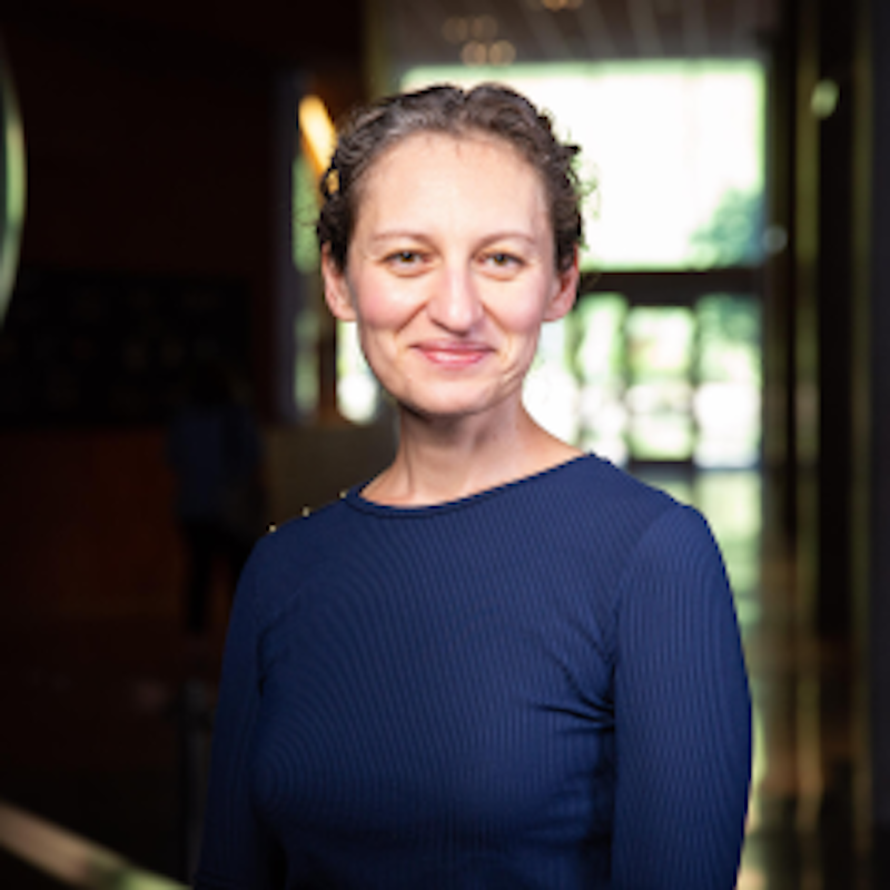 Smiling woman with short hair wearing a dark blue blouse.