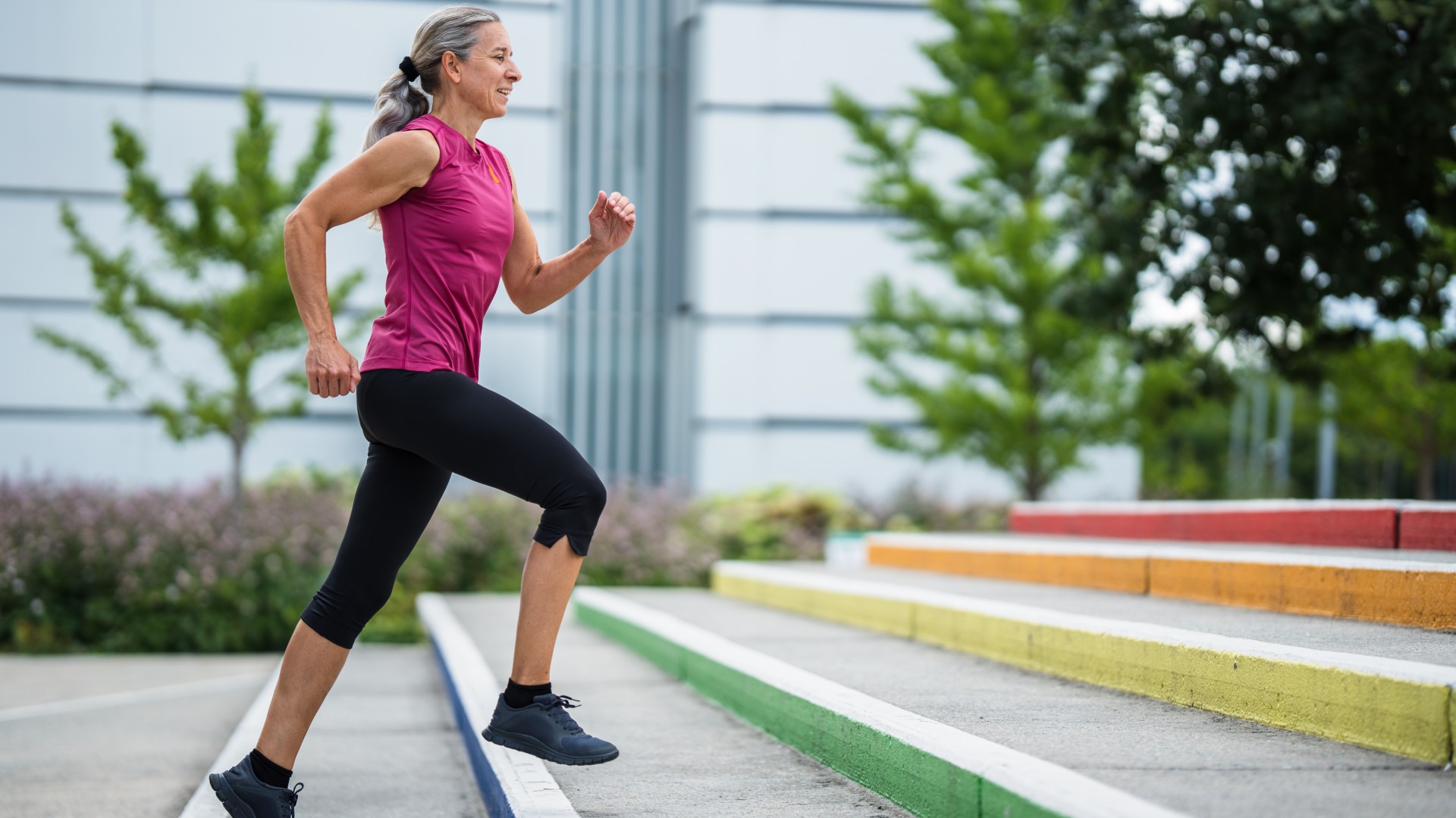 Older woman in activewear power walking up stairs outdoors