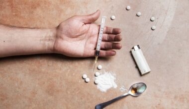 Close up shot of a drug addicts limp arm with drug paraphernalia lying next to it