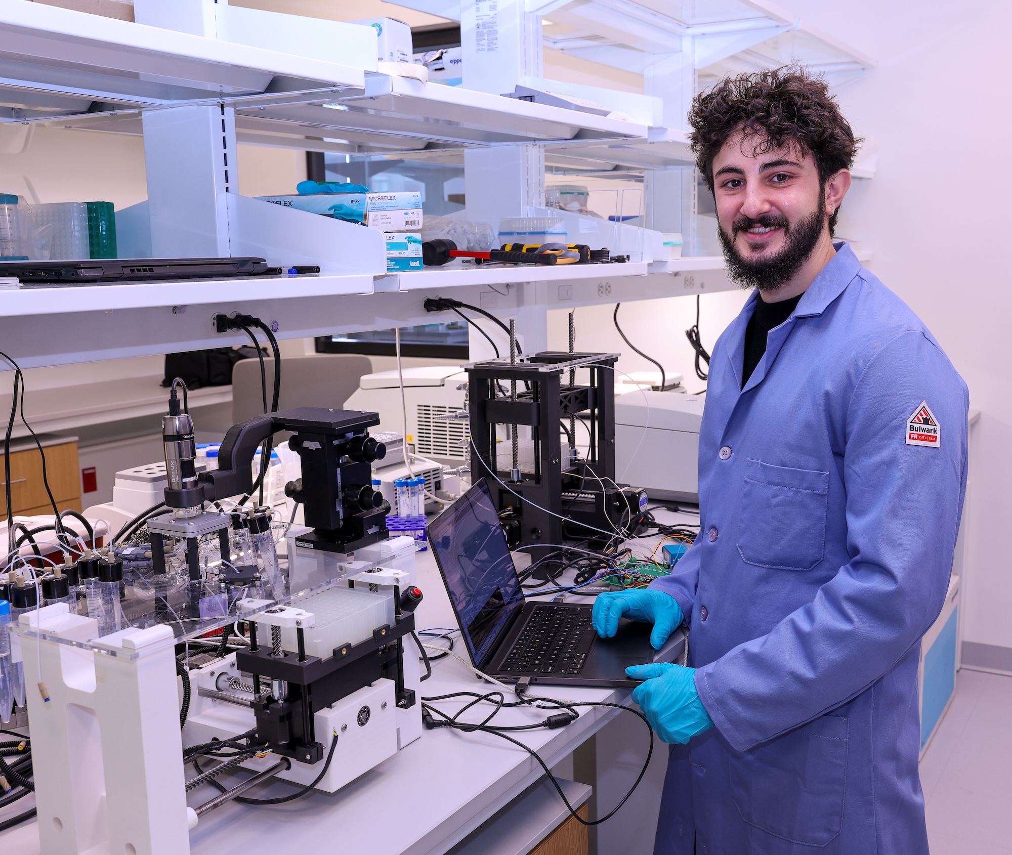 A man in a lab coat stands next to the robot, placed on a lab bench.