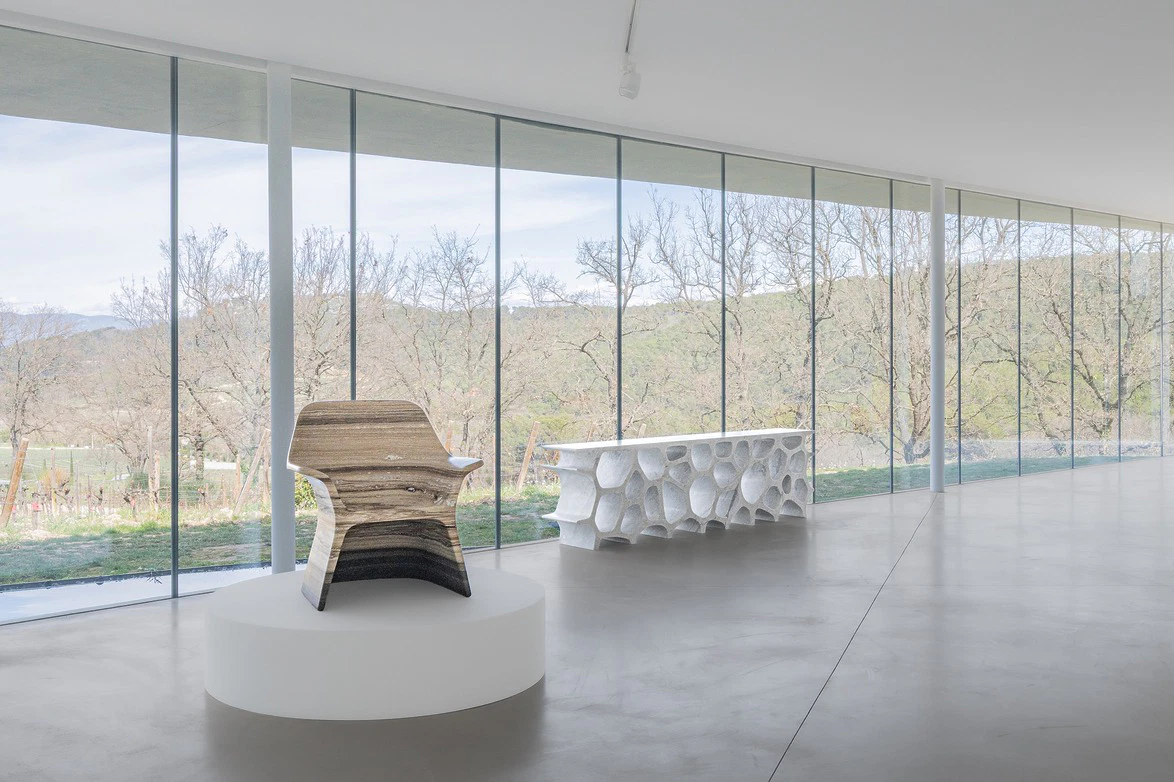 Modern chair and table in minimalist room with large windows and scenic outdoor view.
