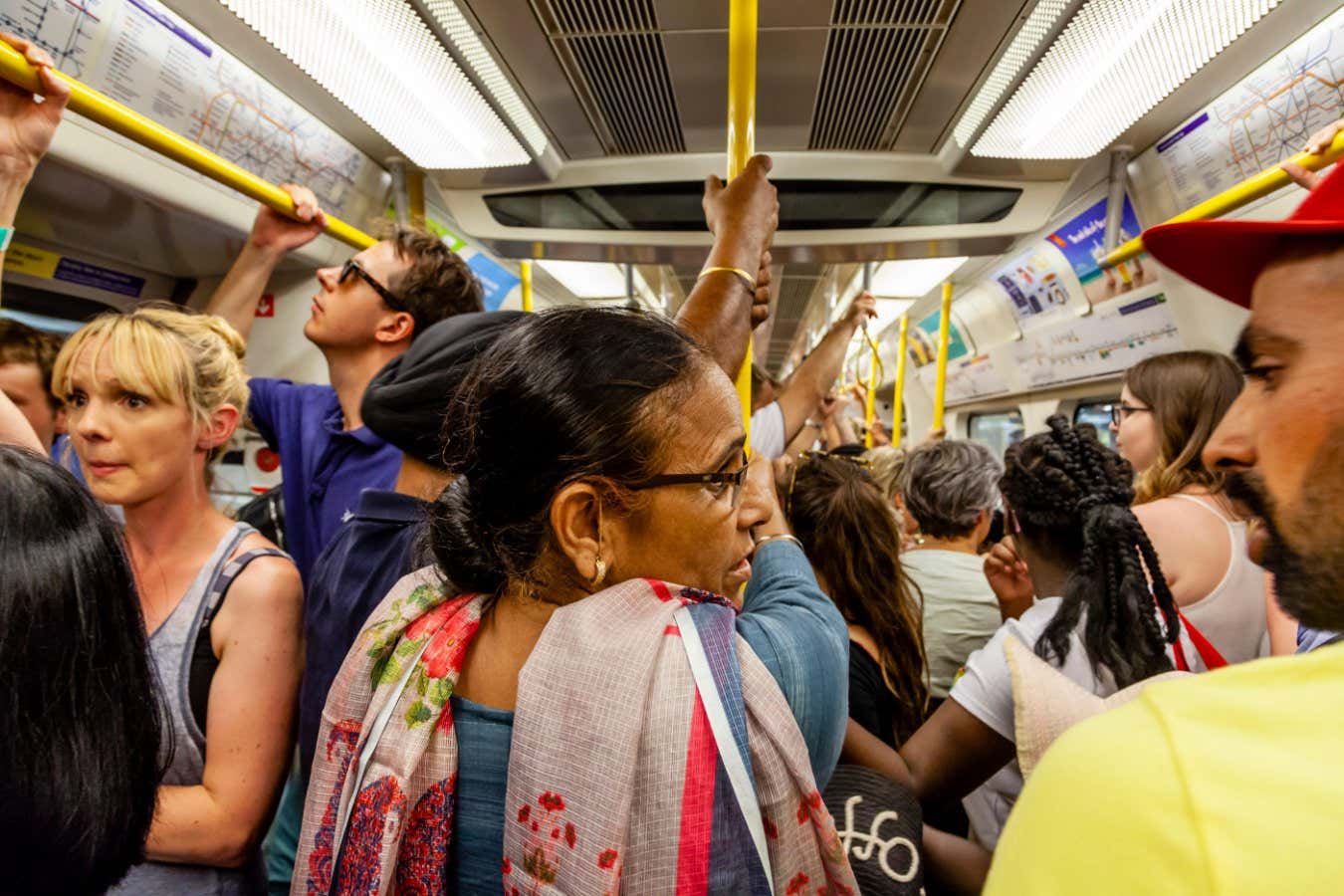 Passengers holding the handrail on a busy London underground train. Challenging your balance can help build core strength