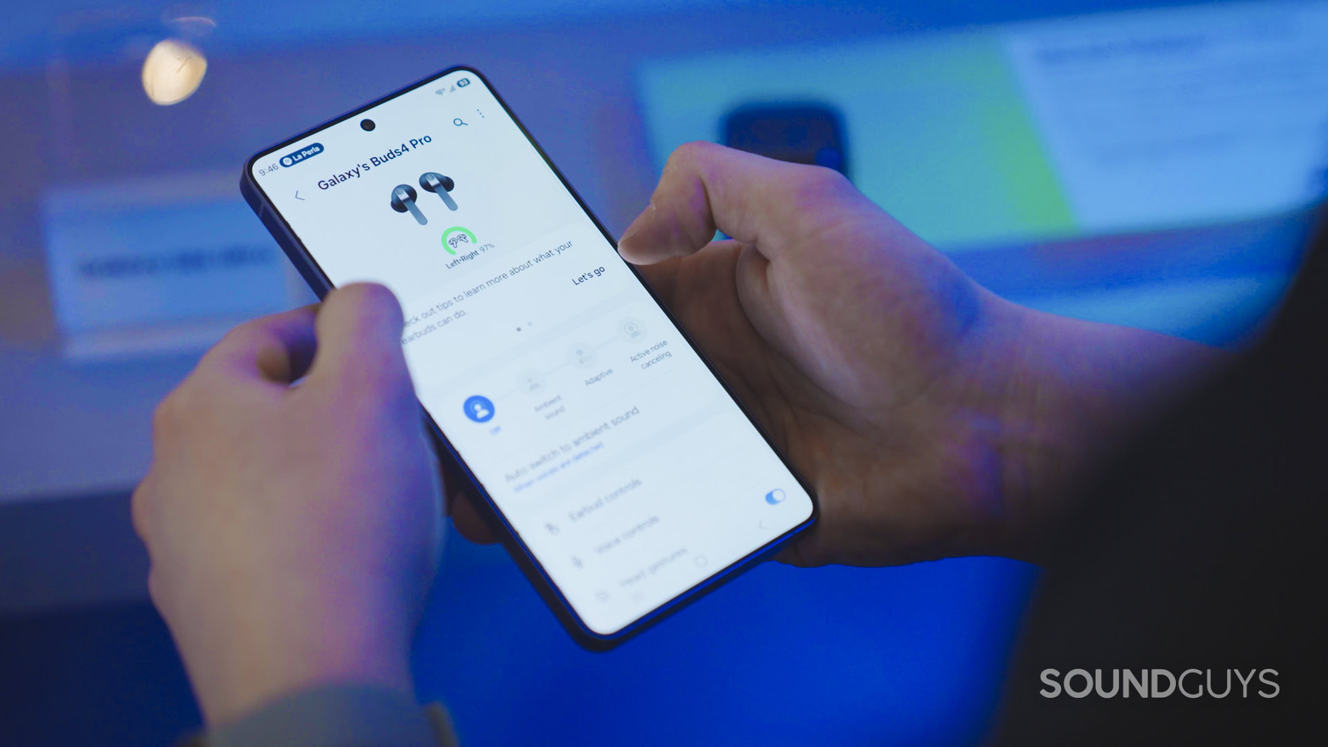 A man holds a new Samsung Phone while controlling the Gear Wearable app.