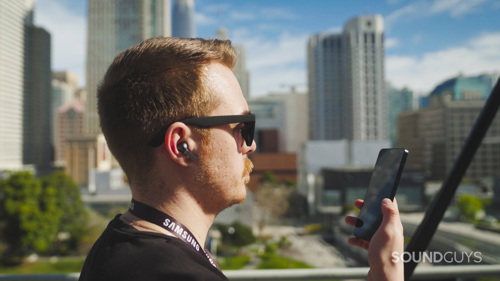 A man wearing the Galaxy Buds4 Pro holding a Samsung S26 phone