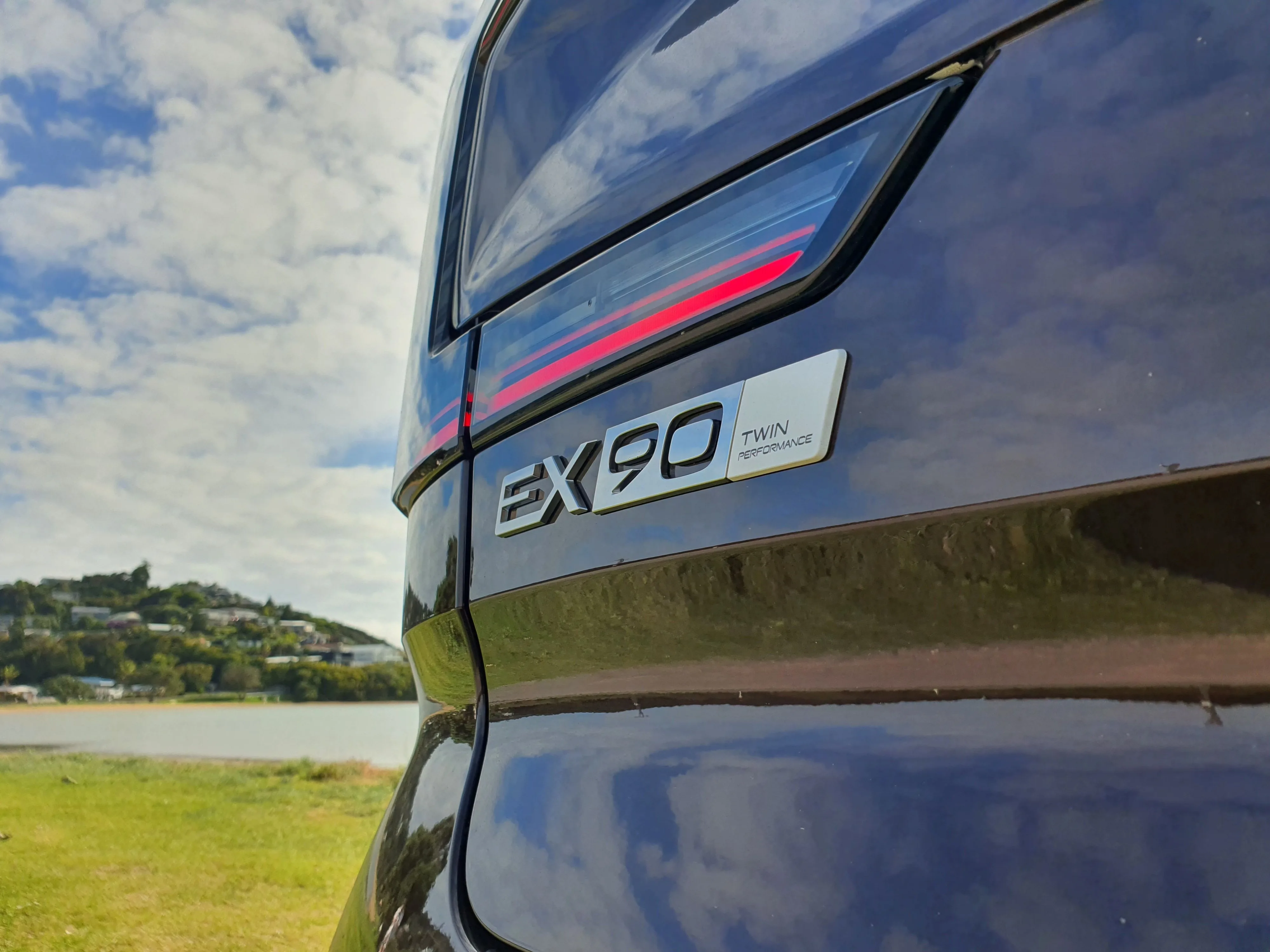 Close up of the EX90 Twin Motor Performance badge on the rear of a 2026 Volvo EX90 Twin Motor Performance in 'Mulberry Red'.