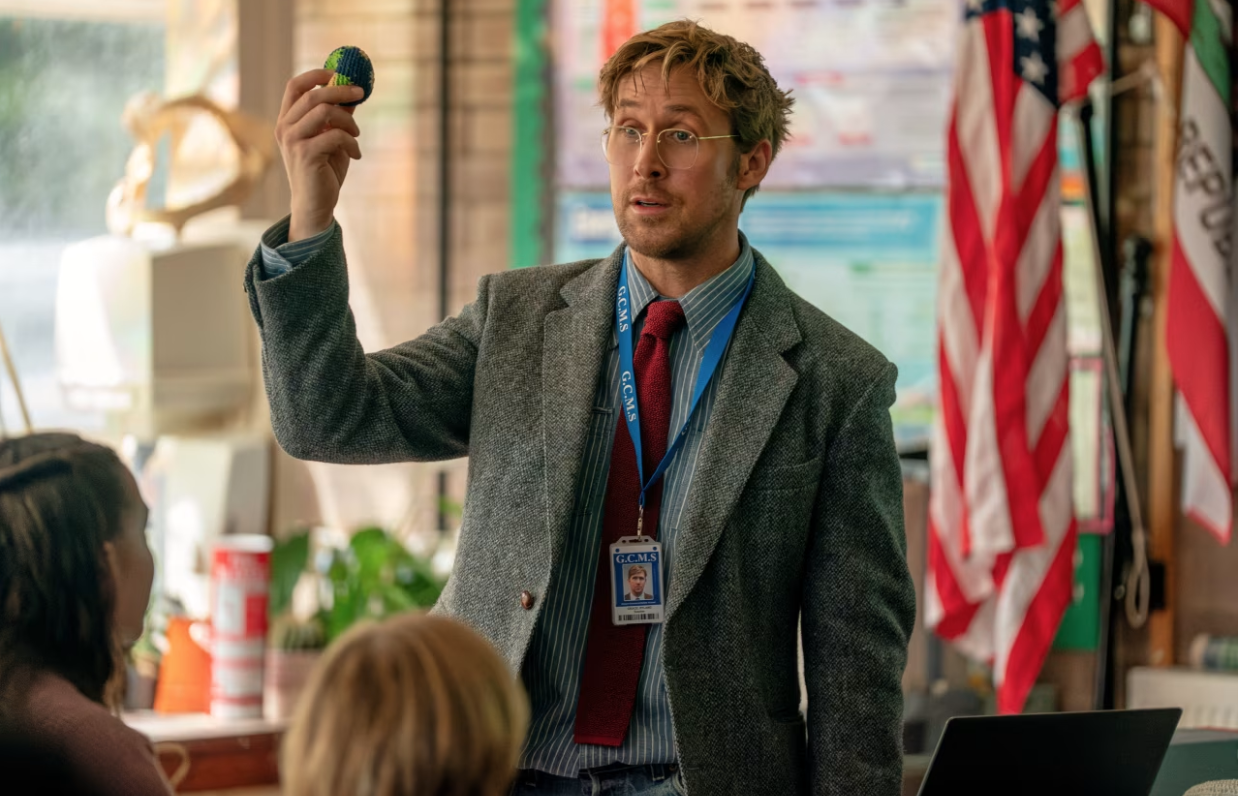 a male teacher holds up a small cloth sack