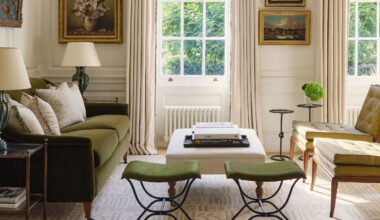 A bright, traditional living room featuring a forest green velvet sofa, olive green mid-century chairs, and twin green stools. Large sash windows are framed by cream drapes and a formal pelmet, with classical oil paintings on the walls.