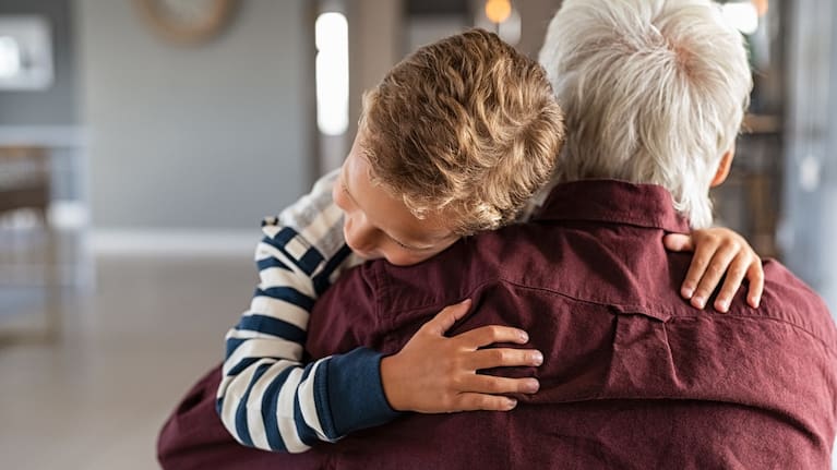 A child hugs their grandparent. 