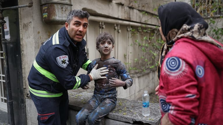 A first responder assists an injured boy following a strike that hit a residential building amid the US-Israeli military campaign in Tehran, Iran.