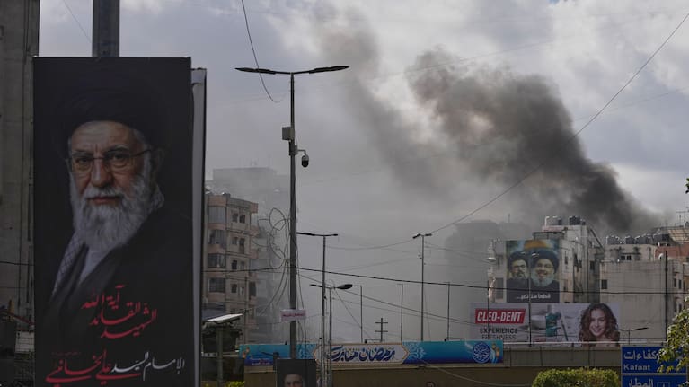 A portrait of Iran's late Supreme Leader Ayatollah Ali Khamenei, left, is seen, as smoke rises following an Israeli airstrike in Dahiyeh, Beirut's southern suburbs, Lebanon, Monday, March 30, 2026. 