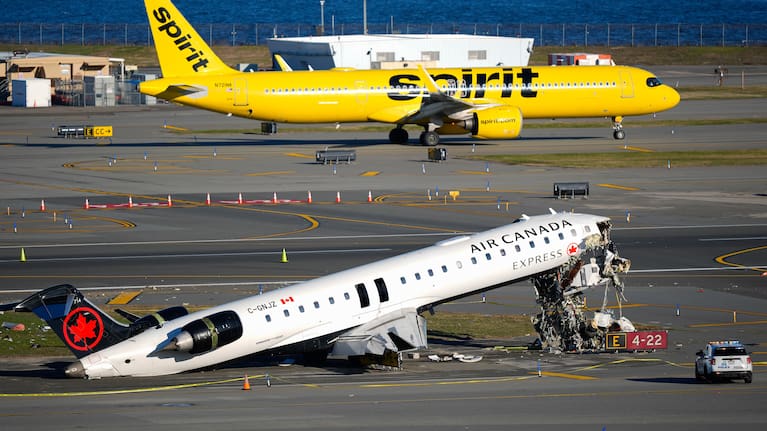 A Spirit Airlines jet taxis past an Air Canada Express jet sitting on the side of a runway, Tuesday, March 24, 2026, where it had collided with a Port Authority fire truck Sunday night at LaGuardia Airport in New York.