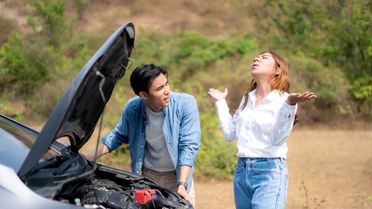 A young couple on the side of the road after a breakdown.