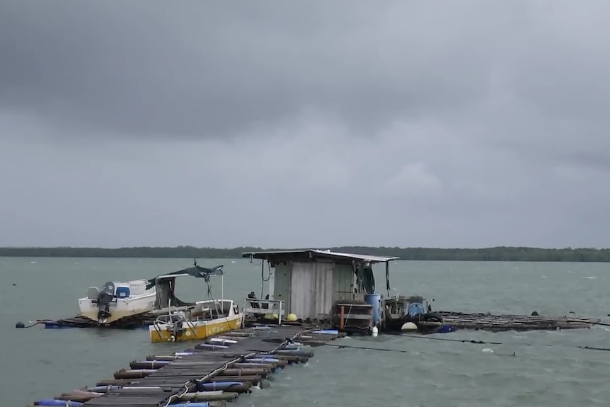 A makeshift jetty and boat shack on water, with two small boats anchored on the side.