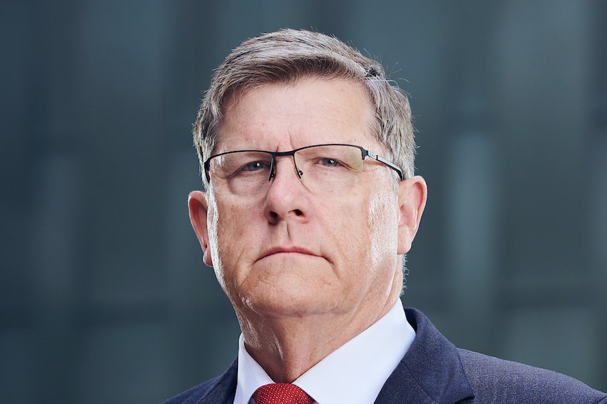 A man in a suit looks at the camera.