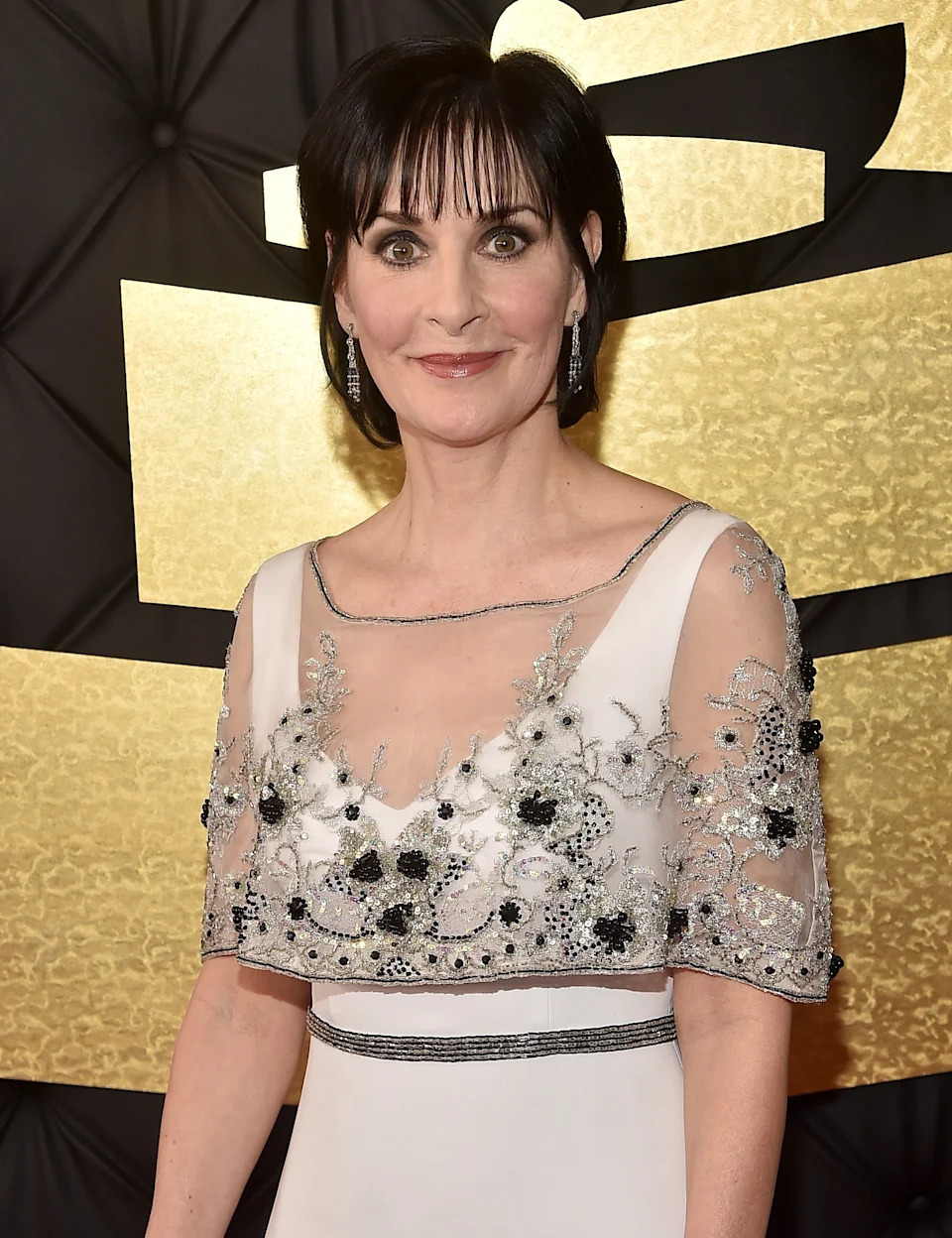 Enya in an elegant gown with floral embroidery, standing on a red carpet