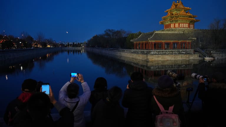 People film the lunar eclipse near the Forbidden City in Beijing, China, Tuesday, March 3, 2026.