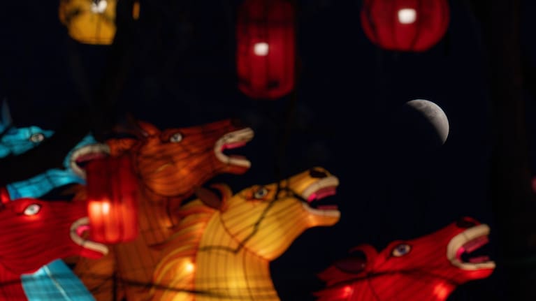 The moon is seen shortly before total eclipse near horse shape lanterns in Beijing, Tuesday, March 3, 2026.