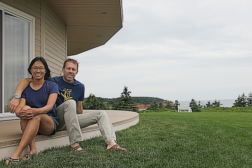 A couple sit together on the deck of a building.