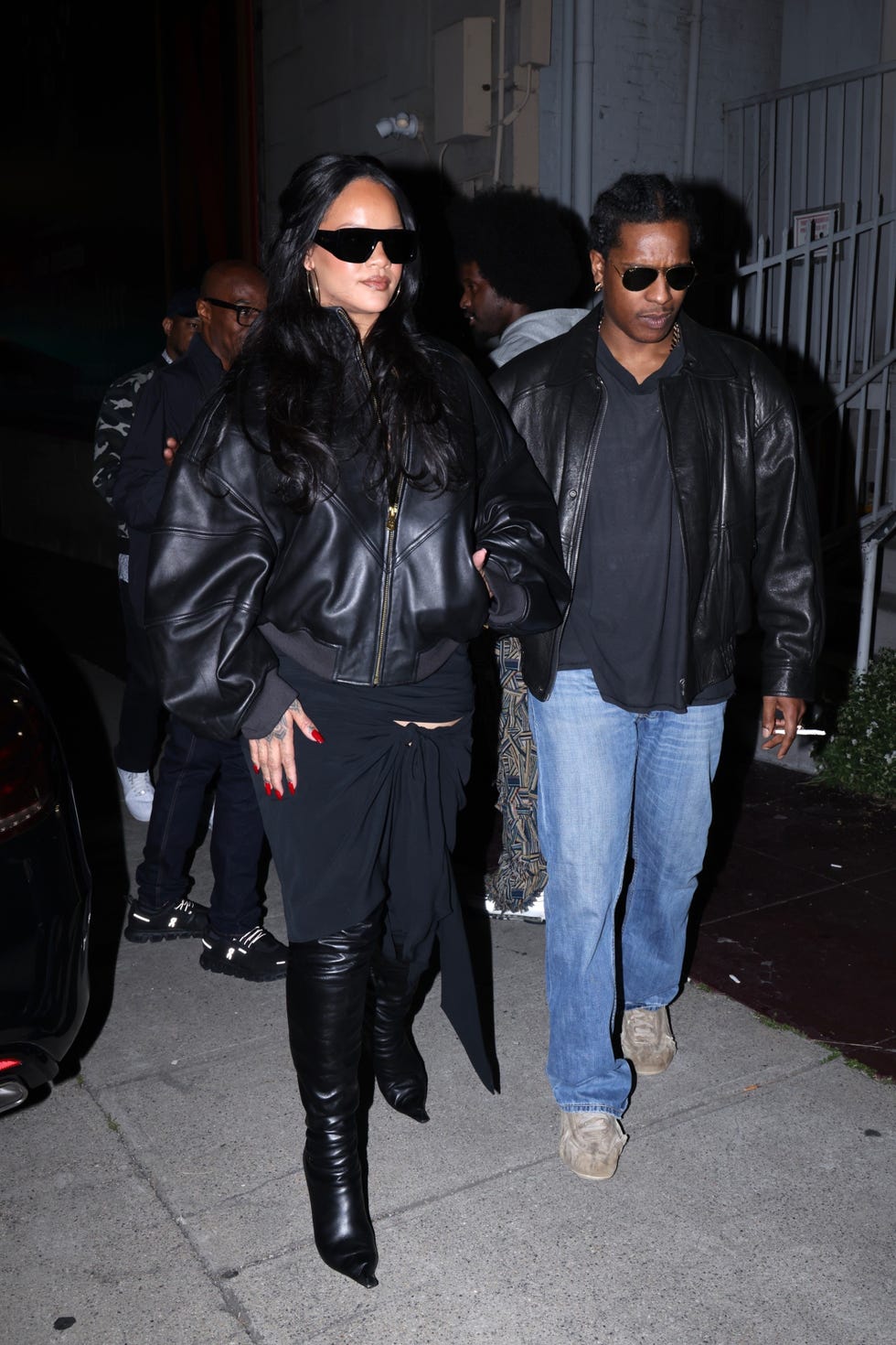 a group of people walking on the sidewalk at night