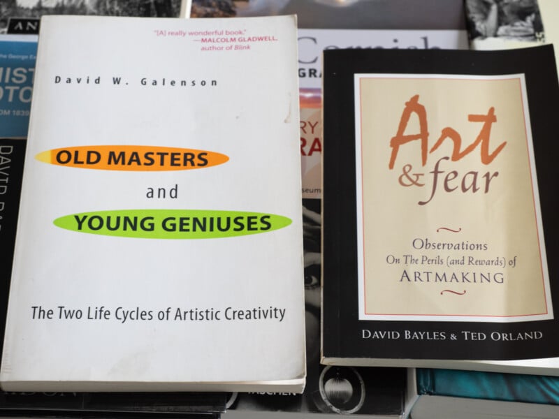 Two books on a table: "Old Masters and Young Geniuses" by David W. Galenson, and "Art & Fear" by David Bayles & Ted Orland. Both discuss creativity and the challenges of making art.