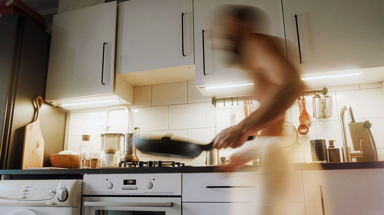 A man holding a frying pan over a stove. 