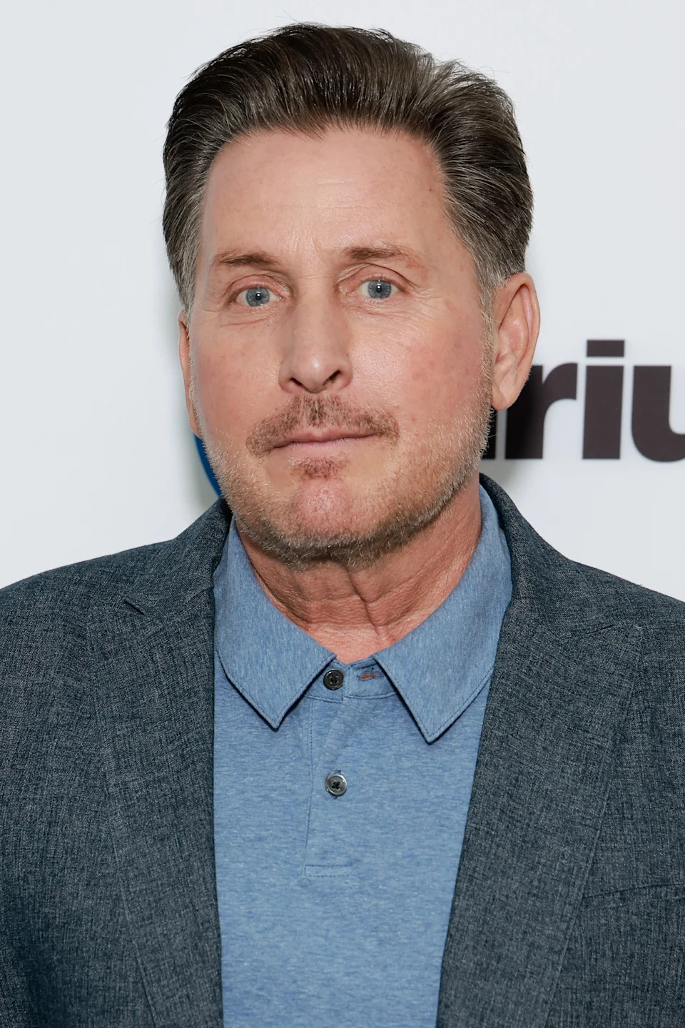 Emilio Estevez in a blue collared shirt and blazer at a media event