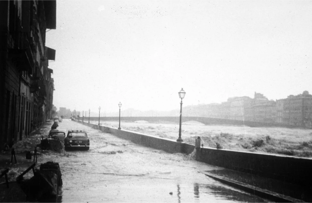 Floodwaters overflowing onto a street in Florence in 1966, submerging cars and reaching the base of buildings.