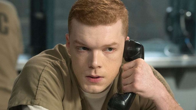 Cameron Monaghan as Ian Gallagher, speaking into a phone in a prison on Shameless.
