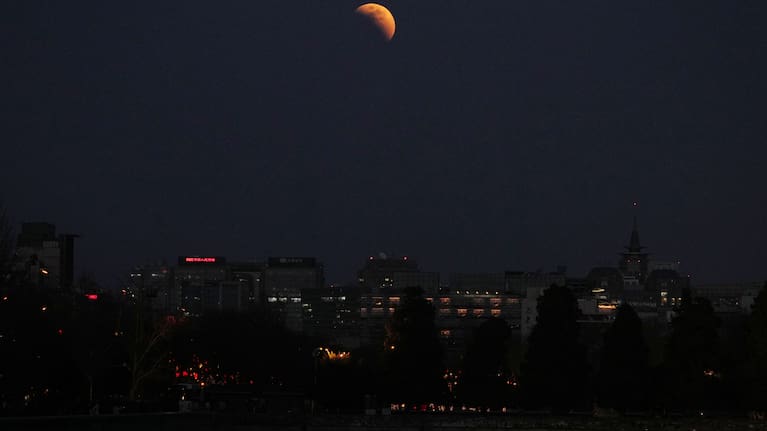 The moon is seen shortly before total lunar eclipse above office buildings in Beijing, China, Tuesday, March 3, 2026.