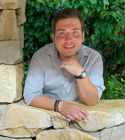 man leaning through an opening in a stone wall