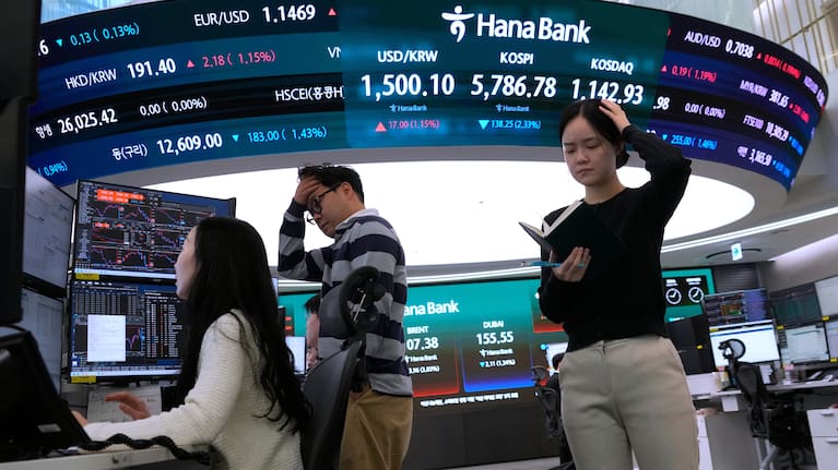 Currency traders work near a screen showing the Korea Composite Stock Price Index (KOSPI), top center, and the foreign exchange rate between US dollar and South Korean won.