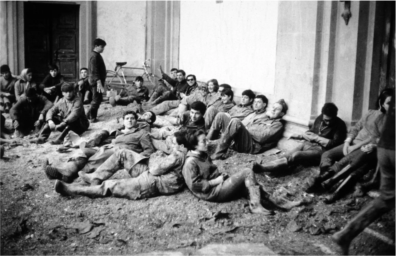 Volunteers resting on muddy ground after the Florence 1966 flood.